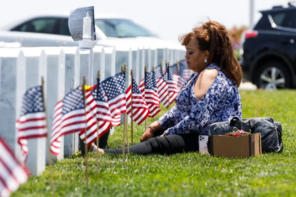 Andrea Freeman, 61, sits at the gravesite of her husband...