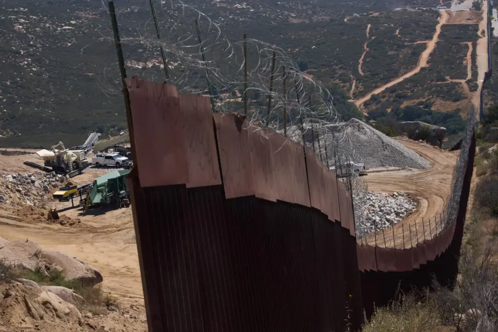 Construction crews work on a new border wall segment