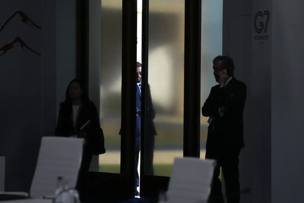 A man looks through a slightly open door before a working session at the G7 summit.
