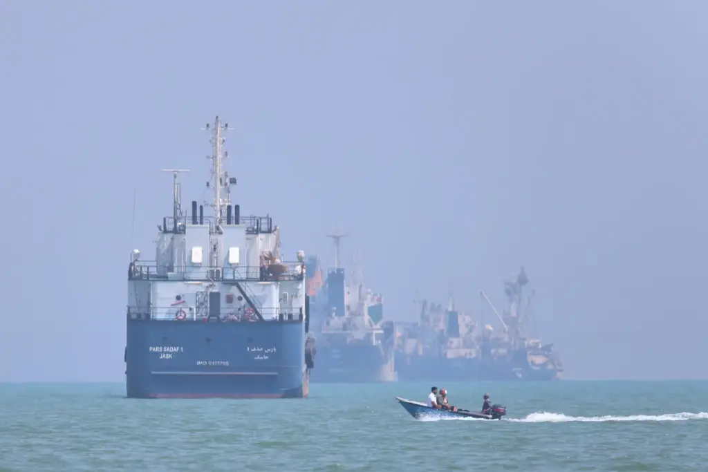 A small motorboat passes anchored vessels in the Strait of...