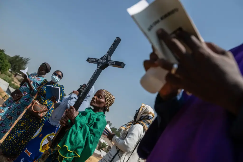 A woman holds a cross during a burial ceremony for...