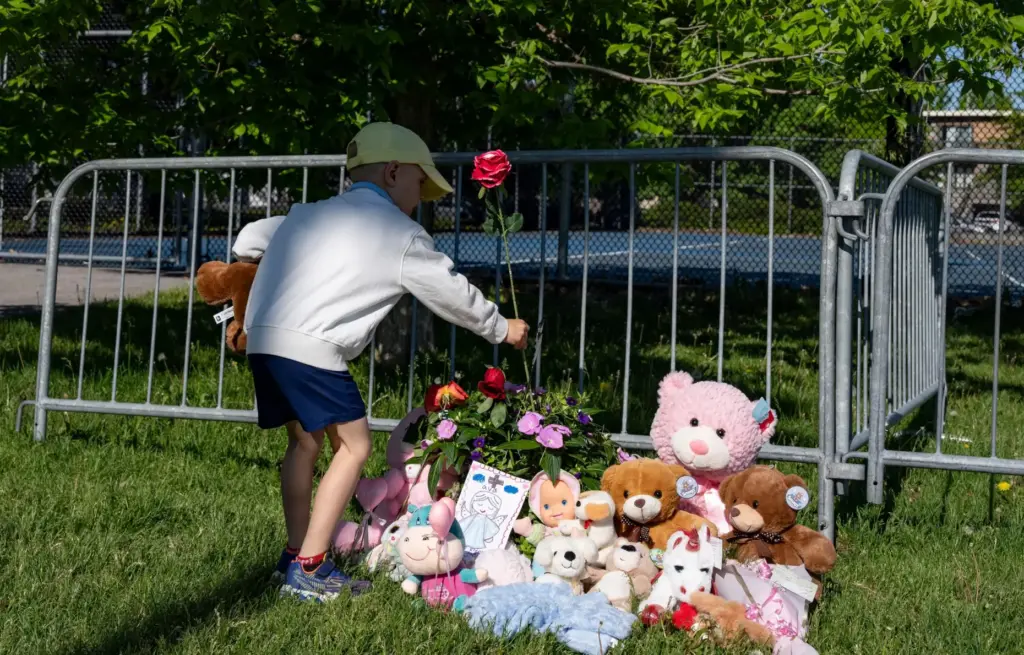 A young boy leaves a flower at a makeshift memorial...
