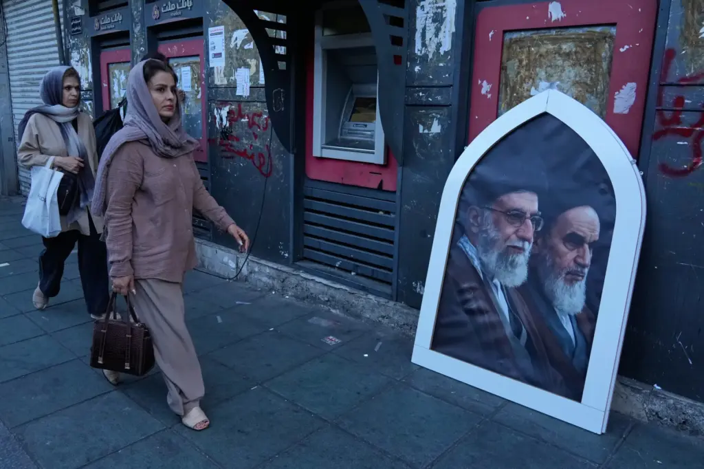 Pedestrians walk past a poster of Supreme Leader Ayatollah Ali Khamenei and Ayatollah Khomeini.