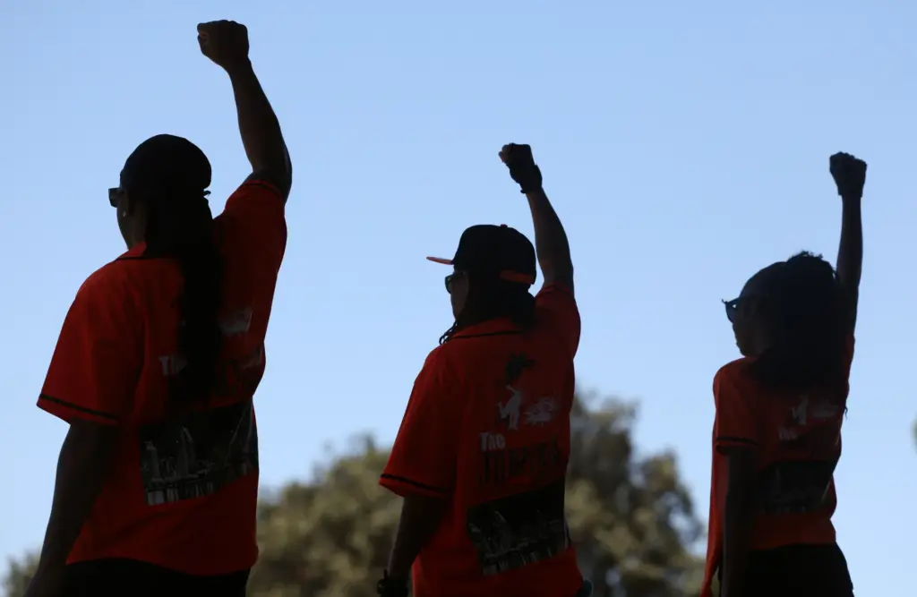 Members of the Junkyard Dance Crew raise their fists at...