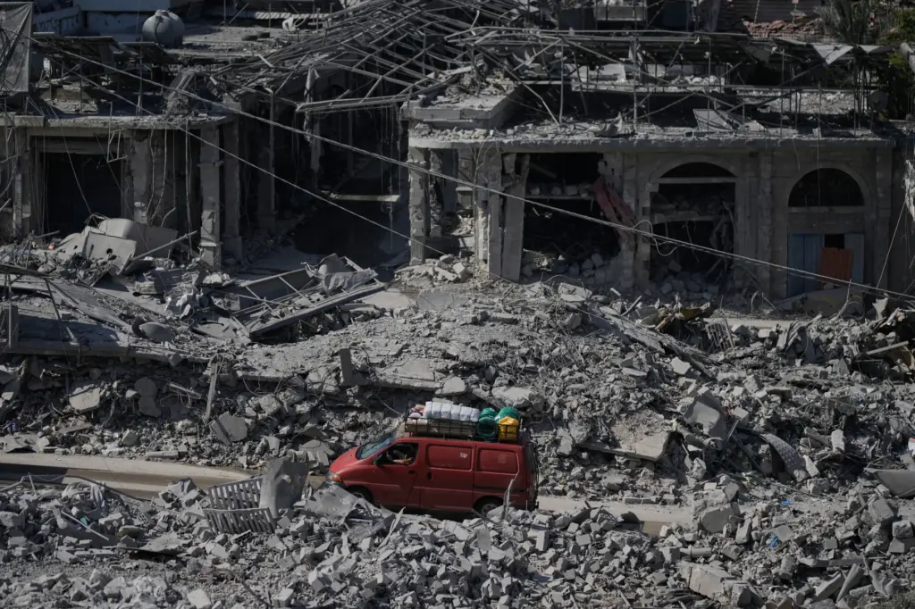 Residents drive past buildings destroyed in previous Israeli airstrikes in Nabatiyeh, Lebanon.