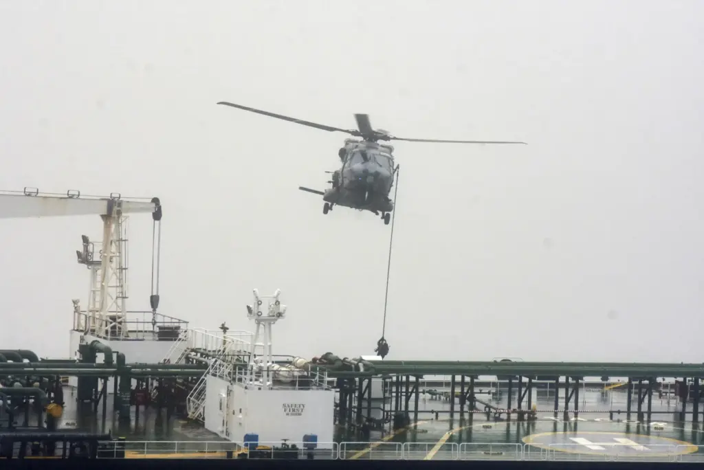 French soldiers use a rope from a NH90 helicopter to intercept an oil tanker.