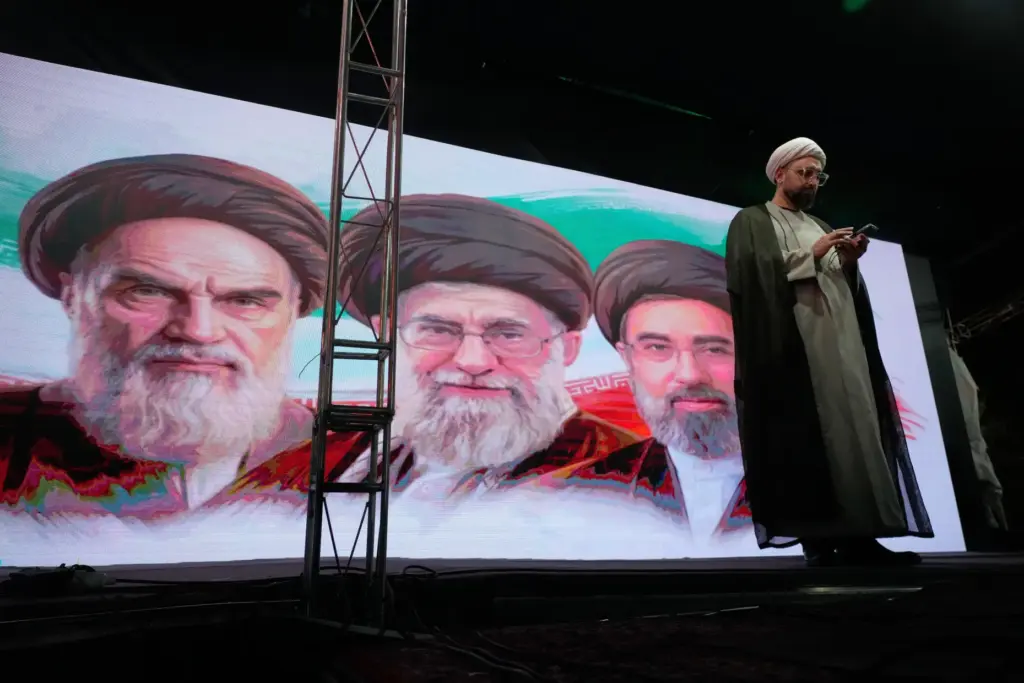 A screen shows portraits of Ayatollah Khomeini, Ayatollah Ali Khamenei and Ayatollah Mojtaba Khamenei.