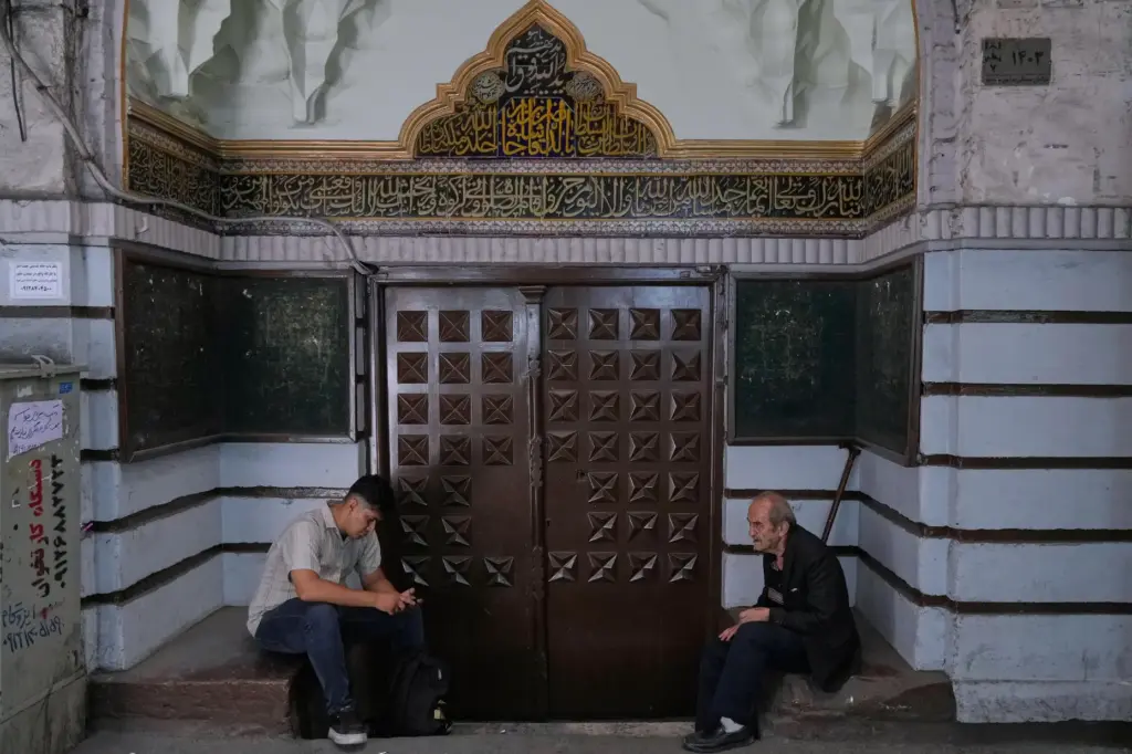 Men sit at the gate of a mosque at Tehran's historic Grand Bazaar.