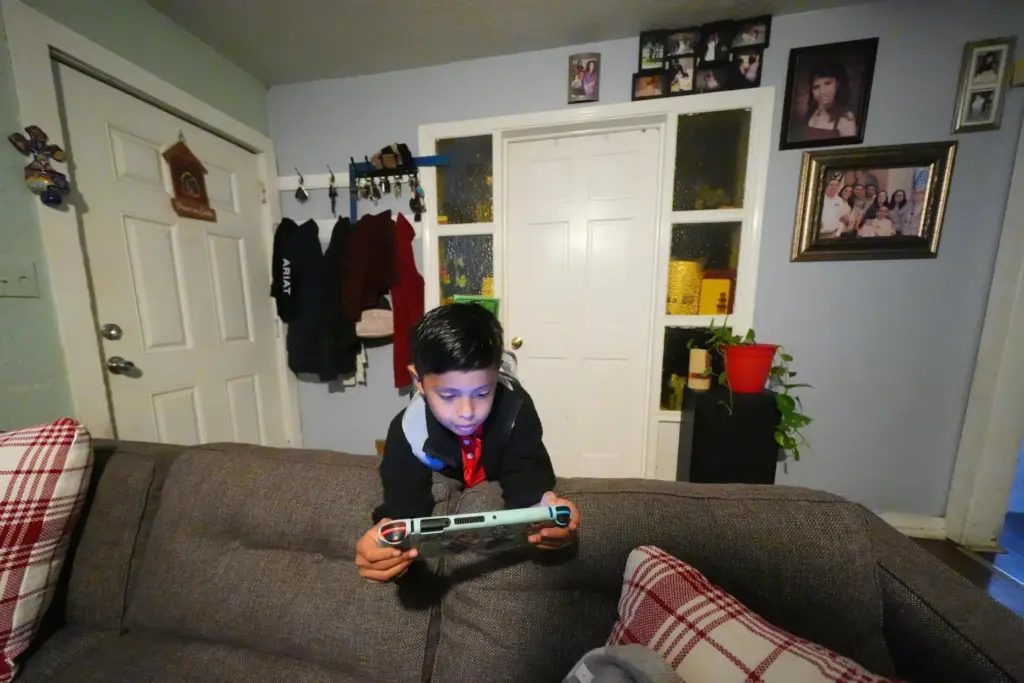 Ian Contreras plays on a gaming device while waiting for...