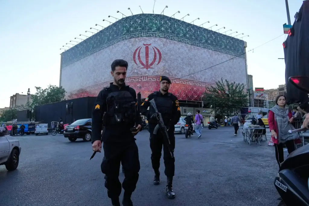 Policemen walk in front of a huge banner showing Iranian...