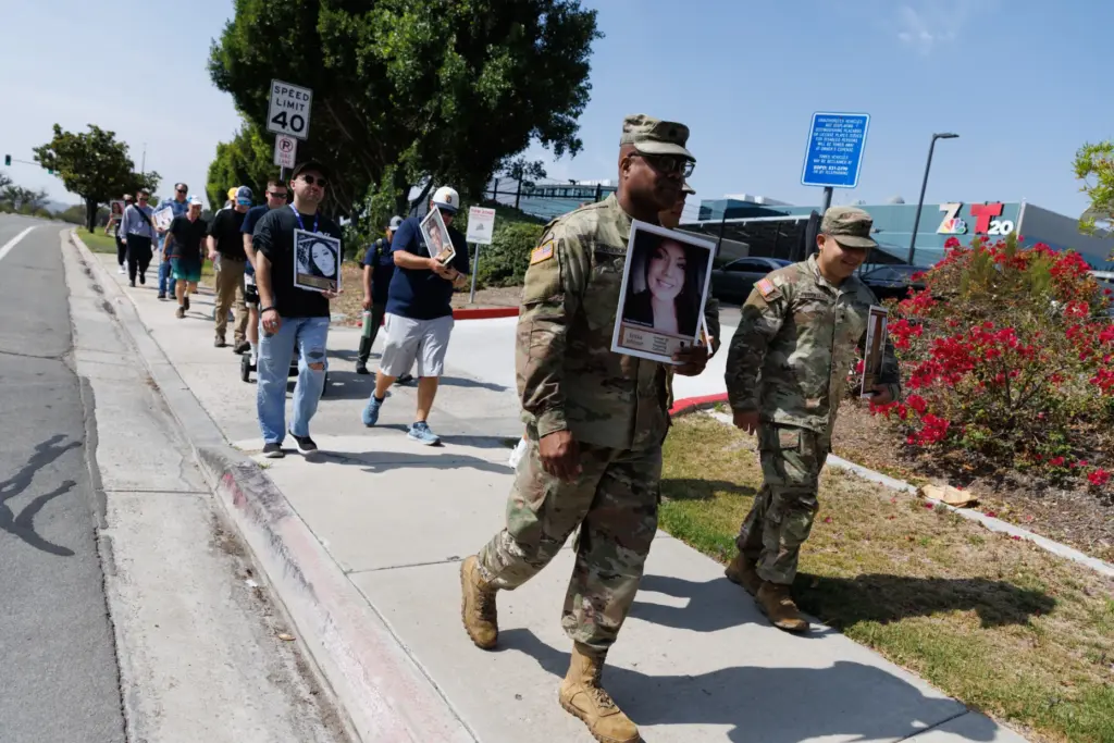Walk for Lives event Participants carry posters displaying photographs of...