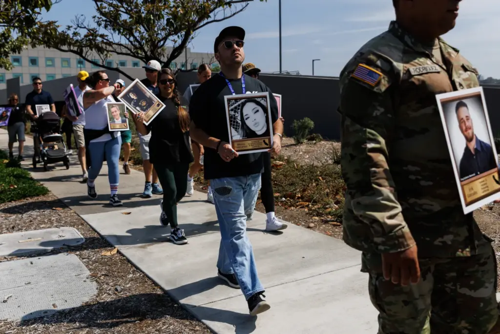 People carry posters displaying photographs of victims who lost their...