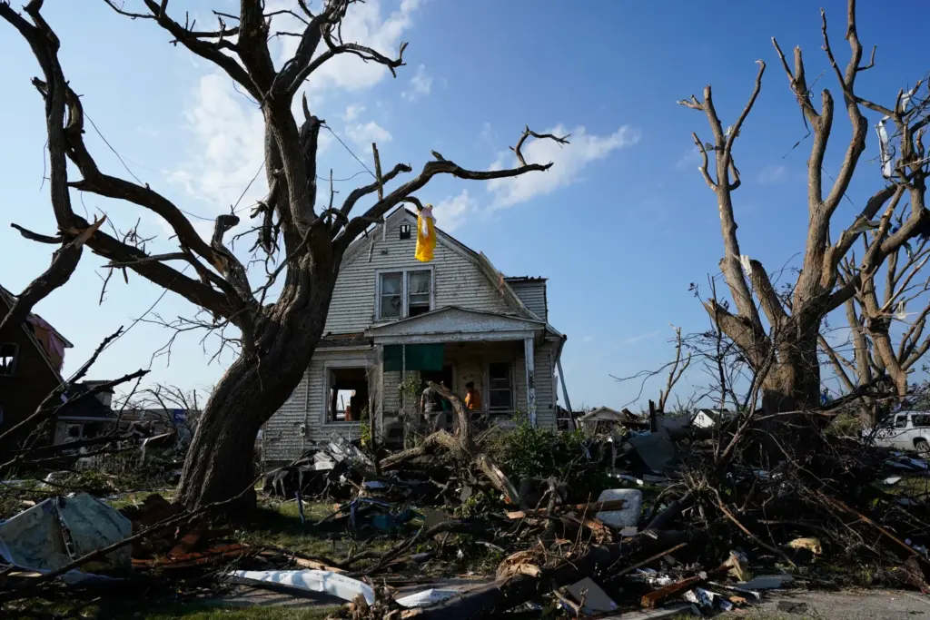 Debris is seen in front of a damaged house after...