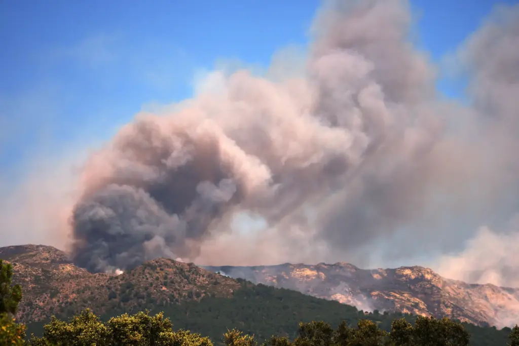 Smoke and flames rise as a wildfire advances near La...