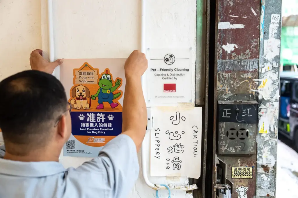 Wan Land Cafe owner Kelvin Chan sticks a poster inside...