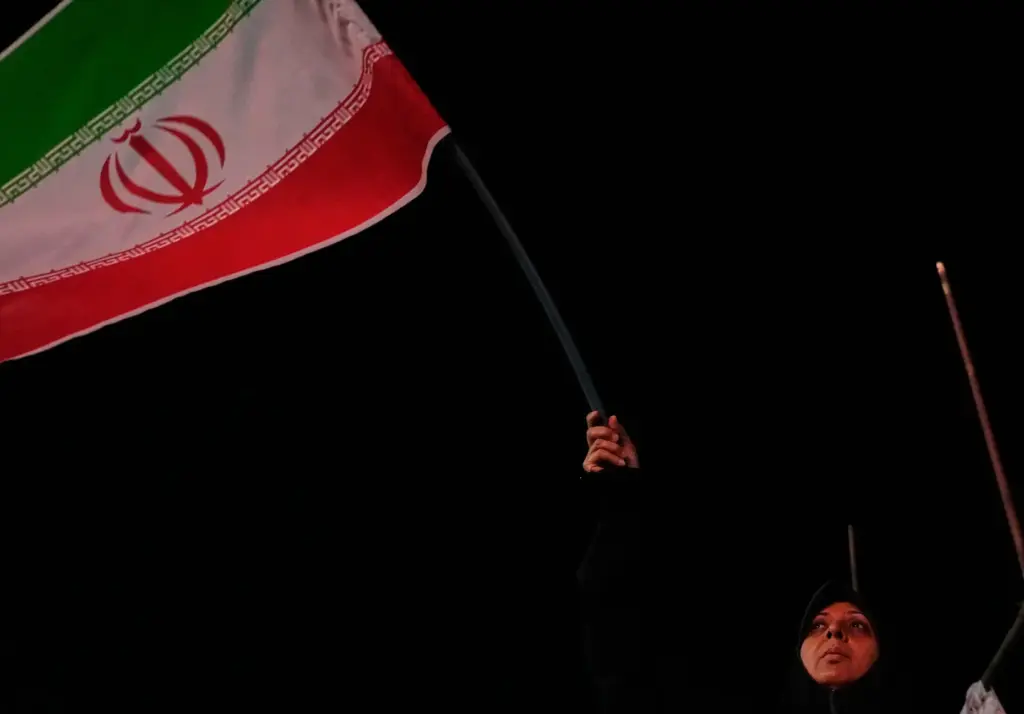 An Iranian pro-government demonstrator waves her country’s flag in a...