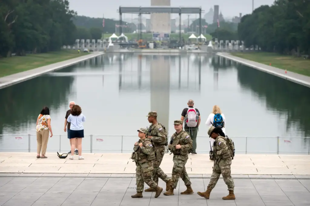National Guard members walk past the Lincoln Memorial Reflecting Pool,...