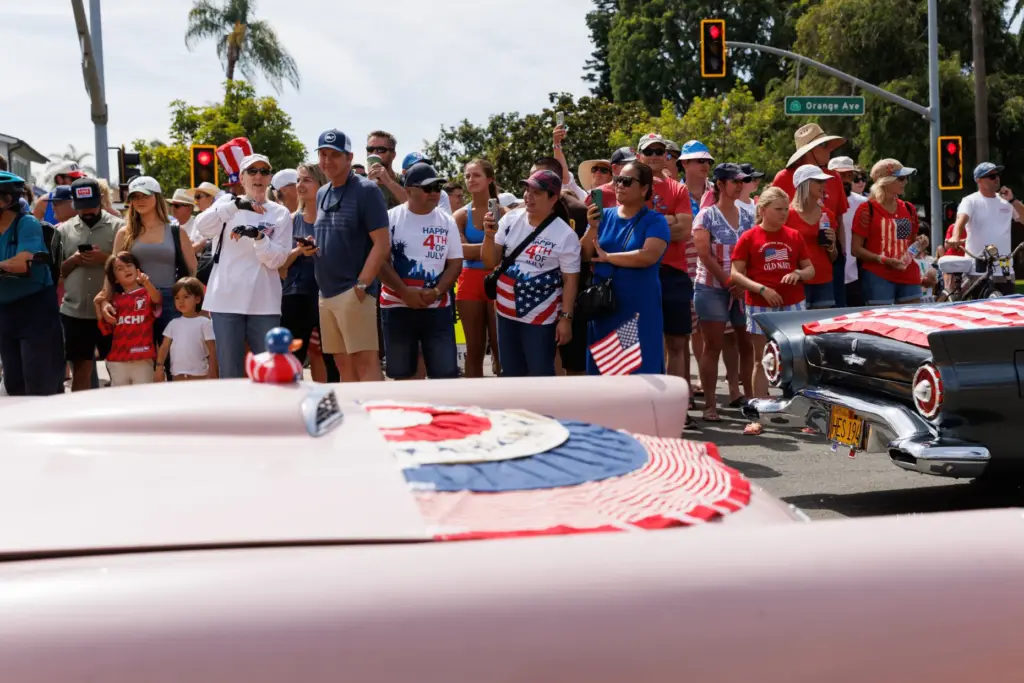 People watch vehicles pass by. (Kristian Carreon / The San...