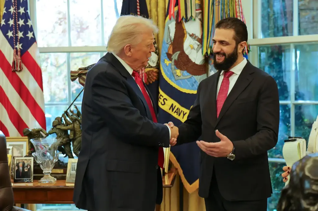 President Donald Trump shakes hands with Syria's President Ahmad al-Sharaa.