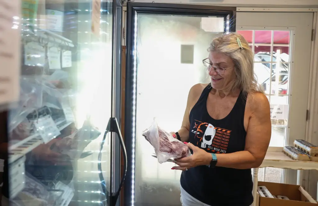 Julie Ninos, of Algonquin, looks over the beef selections at All Grass Farms on June 30, 2026, in Dundee. Ninos shops here regularly and buys beef when she