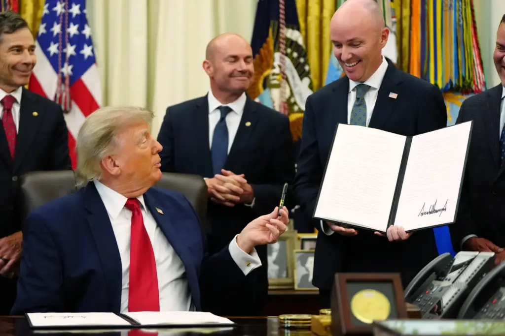 President Donald Trump hands a pen to Utah Gov. Spencer...