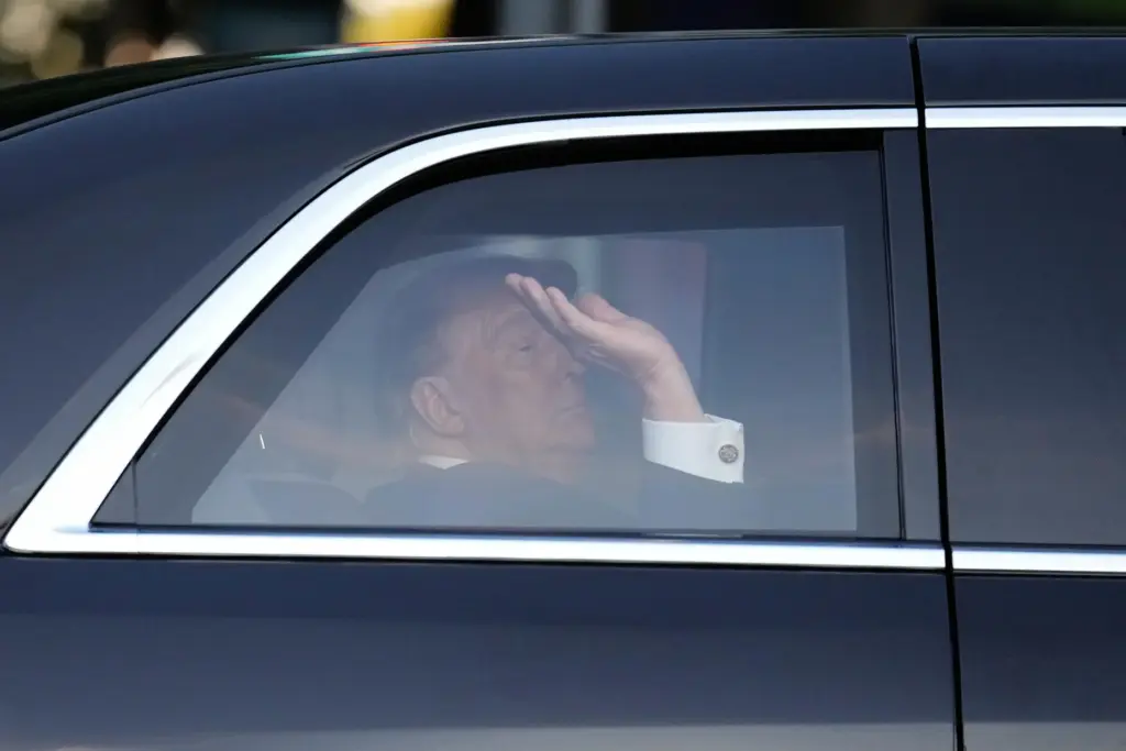 President Donald Trump waves from his motorcade vehicle as he...