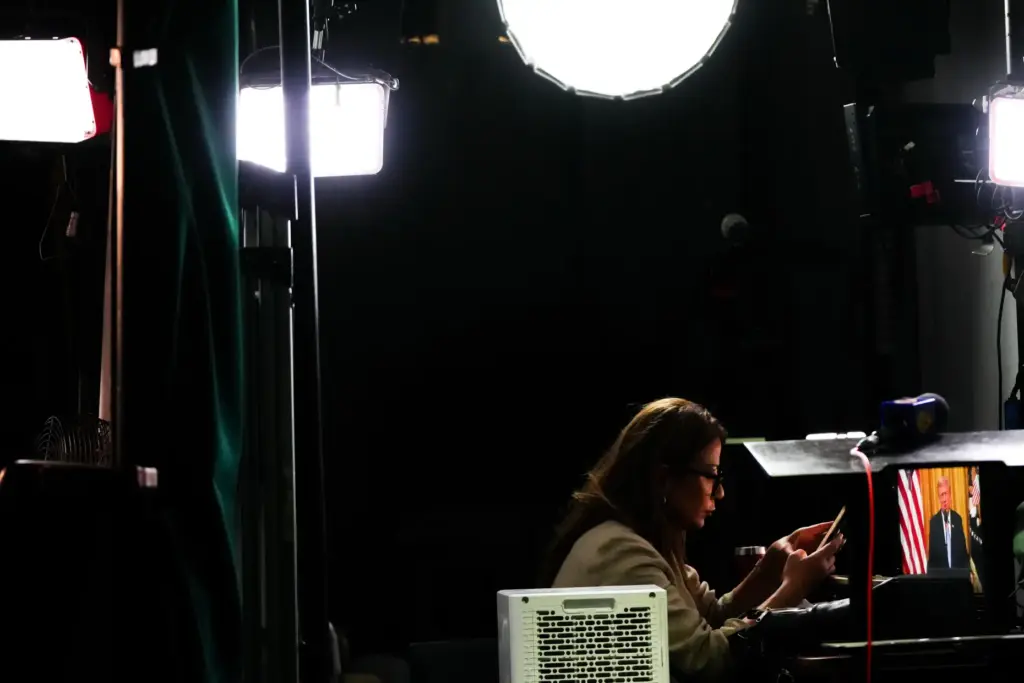 A reporter prepares to film a stand-up as President Donald Trump speaks.