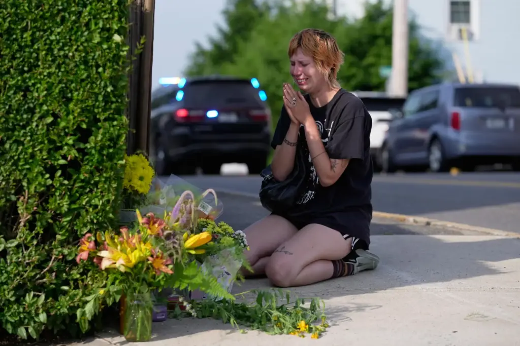 A woman prays after leaving flowers near the scene where a man was killed by ICE.