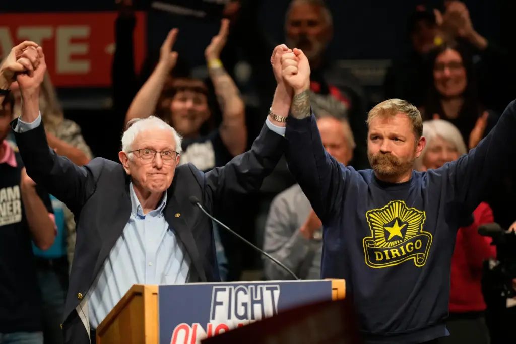 Graham Platner and Sen. Bernie Sanders join hands.