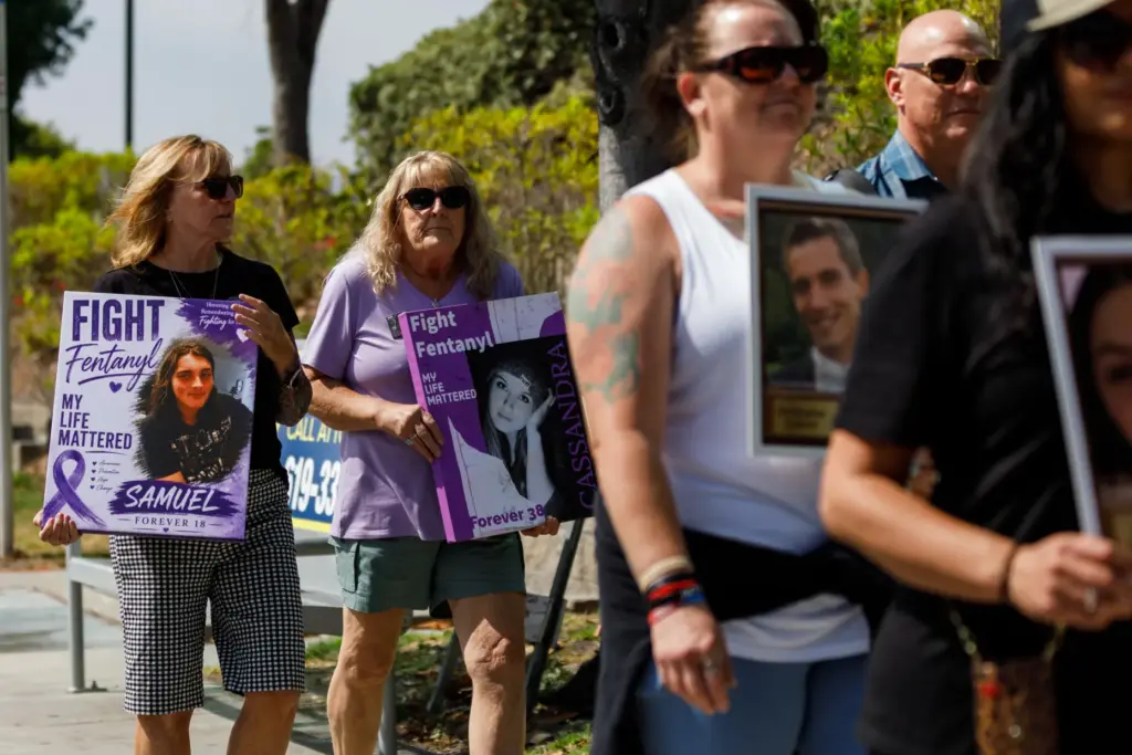 Cindy Parente and Caroline Walker carry posters of their children,...
