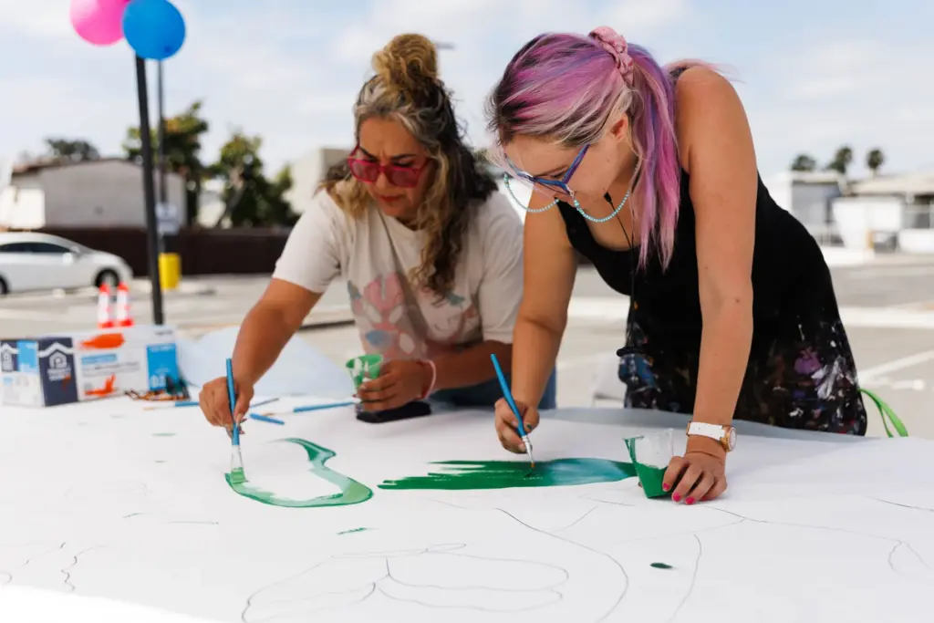 Francia Pinillos and Leslie Monroy paint during a community mural...
