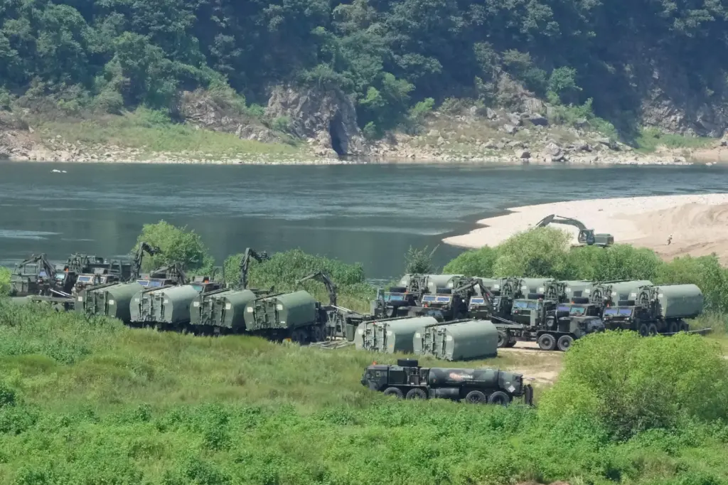 The U.S. Army's armored vehicles gather to cross a river at a training field.