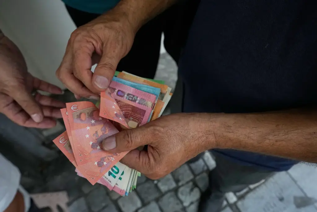 A money exchanger counts Euro bank notes at Ferdowsi square.