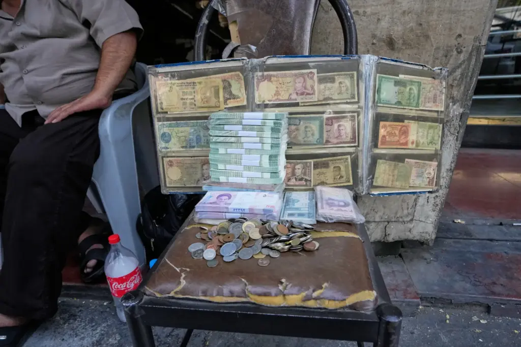 Current and pre-revolution Iranian banknotes are displayed by a street money exchanger.