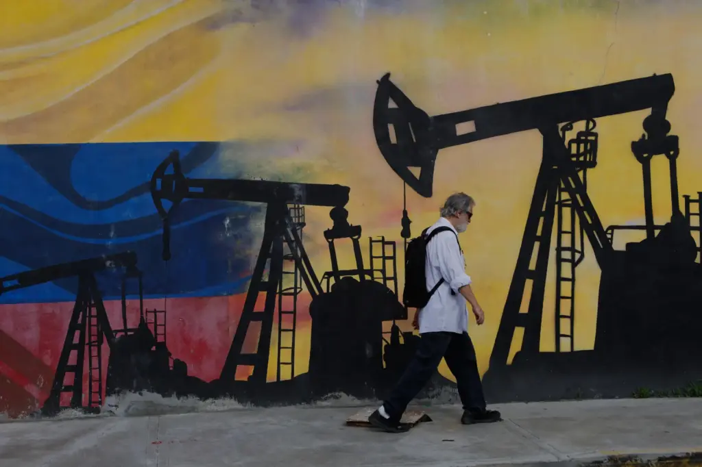 A pedestrian walks past a mural featuring oil wells in...