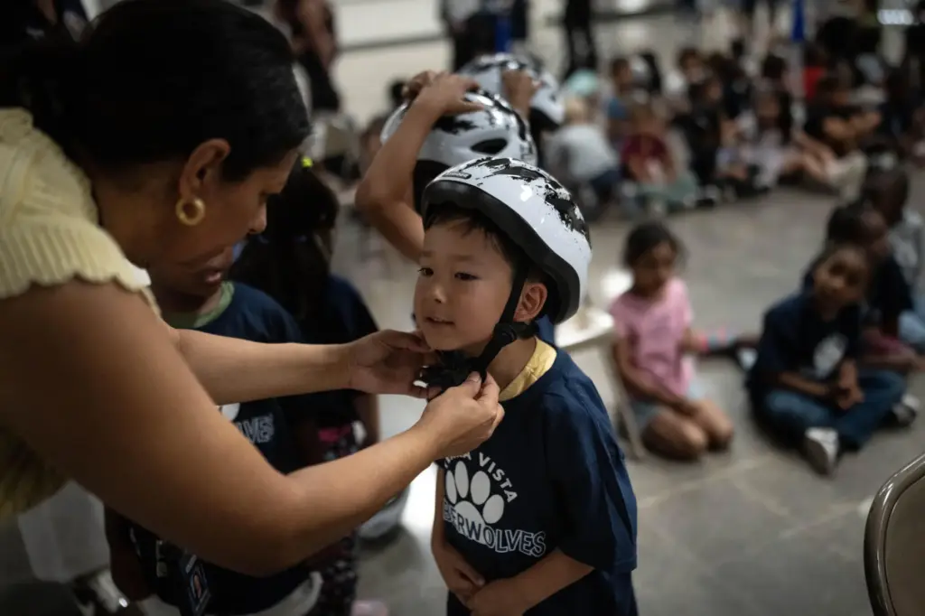 Teachers help students put on their helmets during a learn-to-ride program.