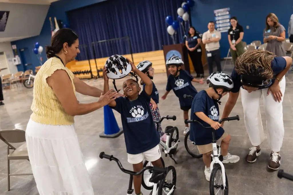 Kindergartner Carson Hagens smiles as he removes his helmet after riding a bike.