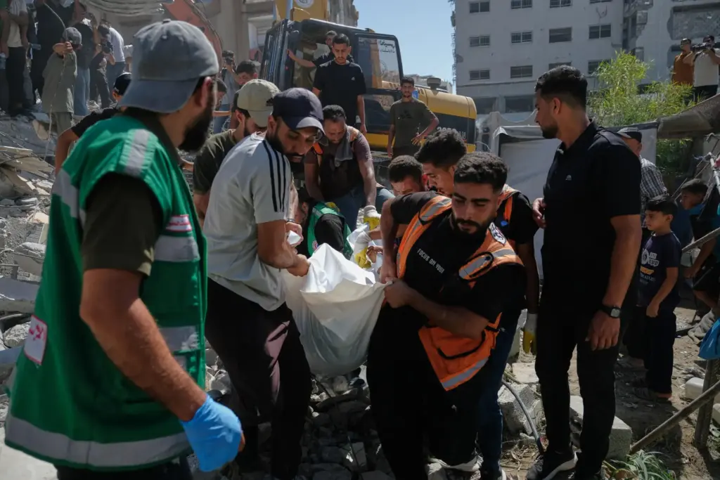 Palestinian civil defense crews carry a body from the rubble of a collapsed building.
