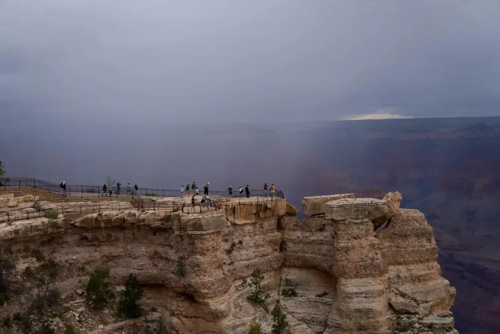 People stand at the rim of the Grand Canyon as...