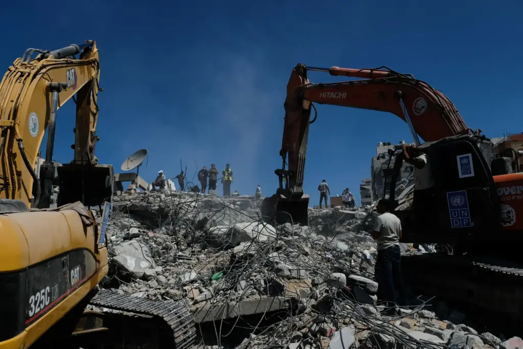 Palestinian civil defense crews search for bodies and survivors in the rubble of a collapsed building.