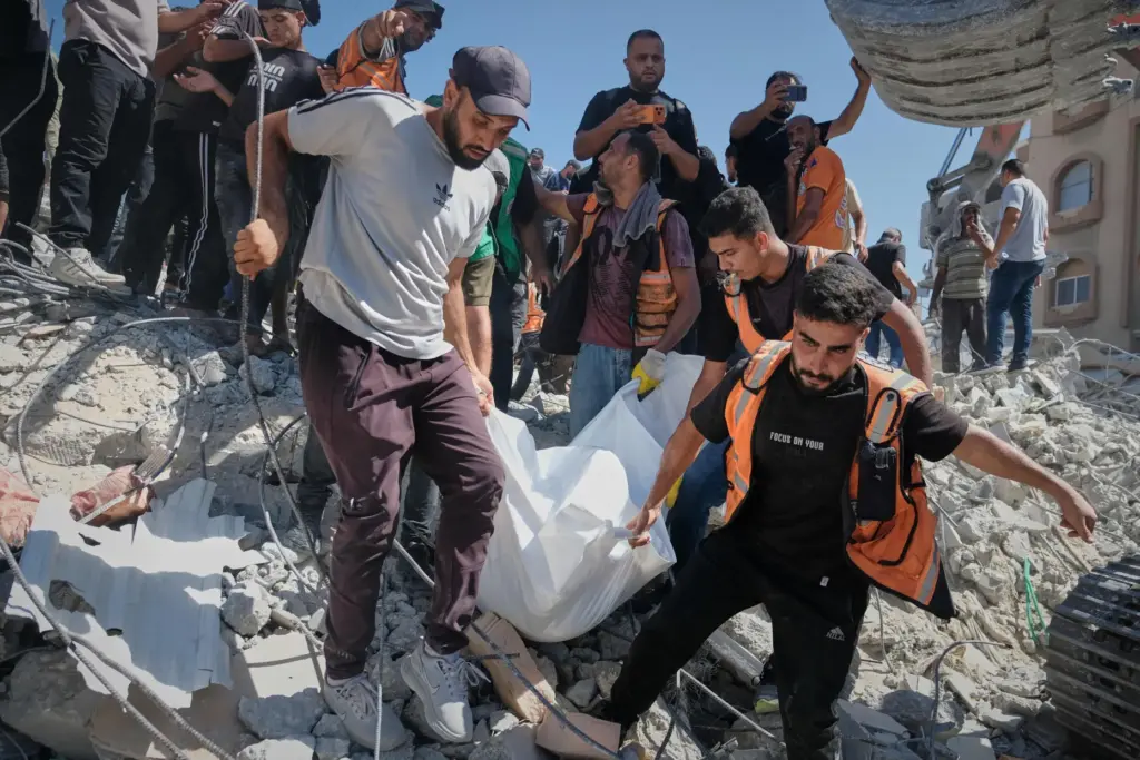Palestinian civil defense crews carry a body from the rubble of a collapsed building.