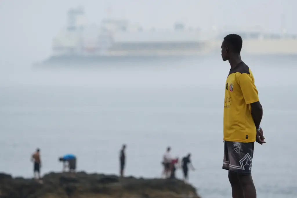 Migrants stand at El Trampolín beach in the Spanish exclave...