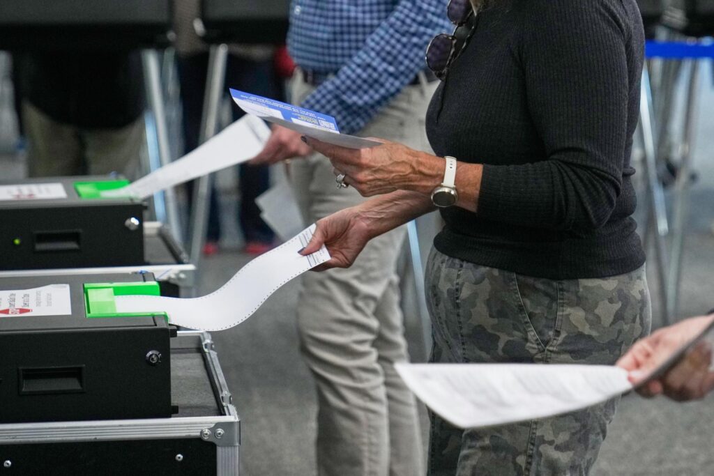 Voters enter their ballots into scanners at early in-person voting...