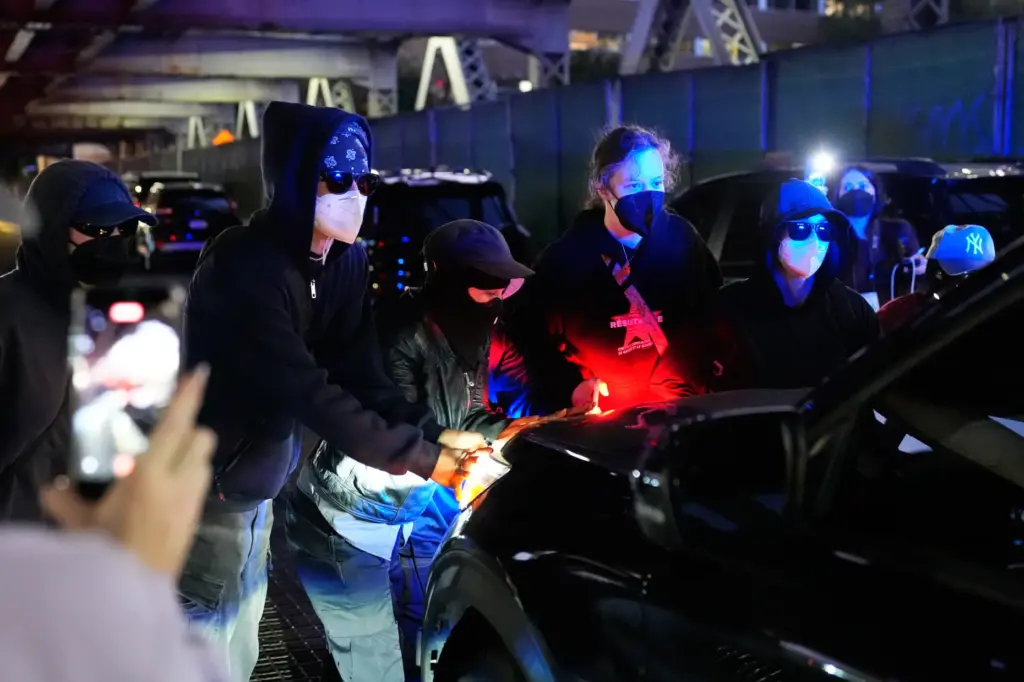 People block a car from driving near the scene of...