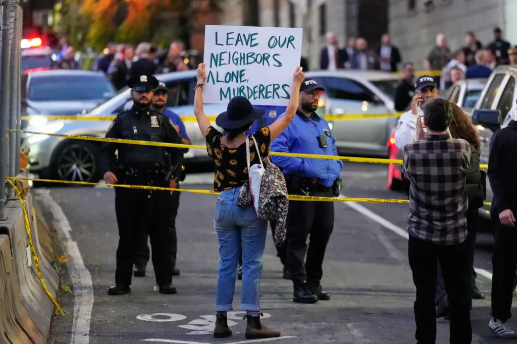 A person holds a sign at the scene of a...
