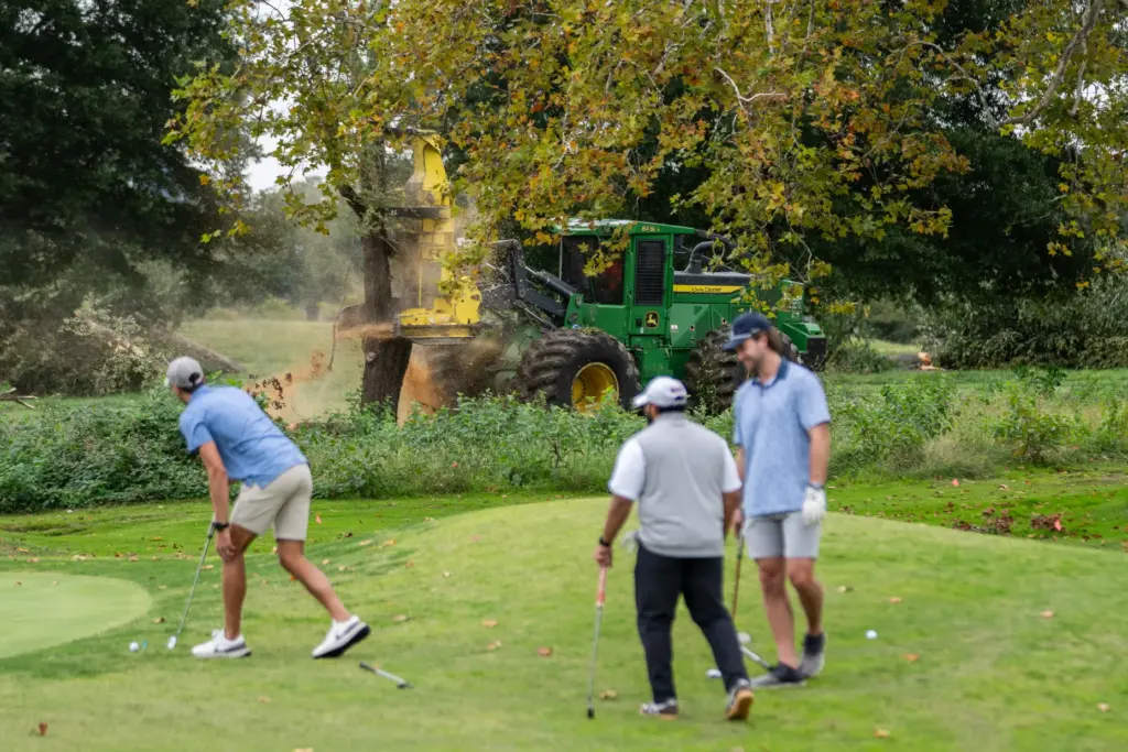 Golfers pass workers as the National Park Service begins cutting...