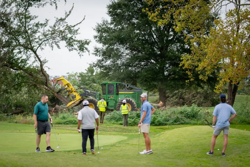 Golfers pass workers as the National Park Service begins cutting...